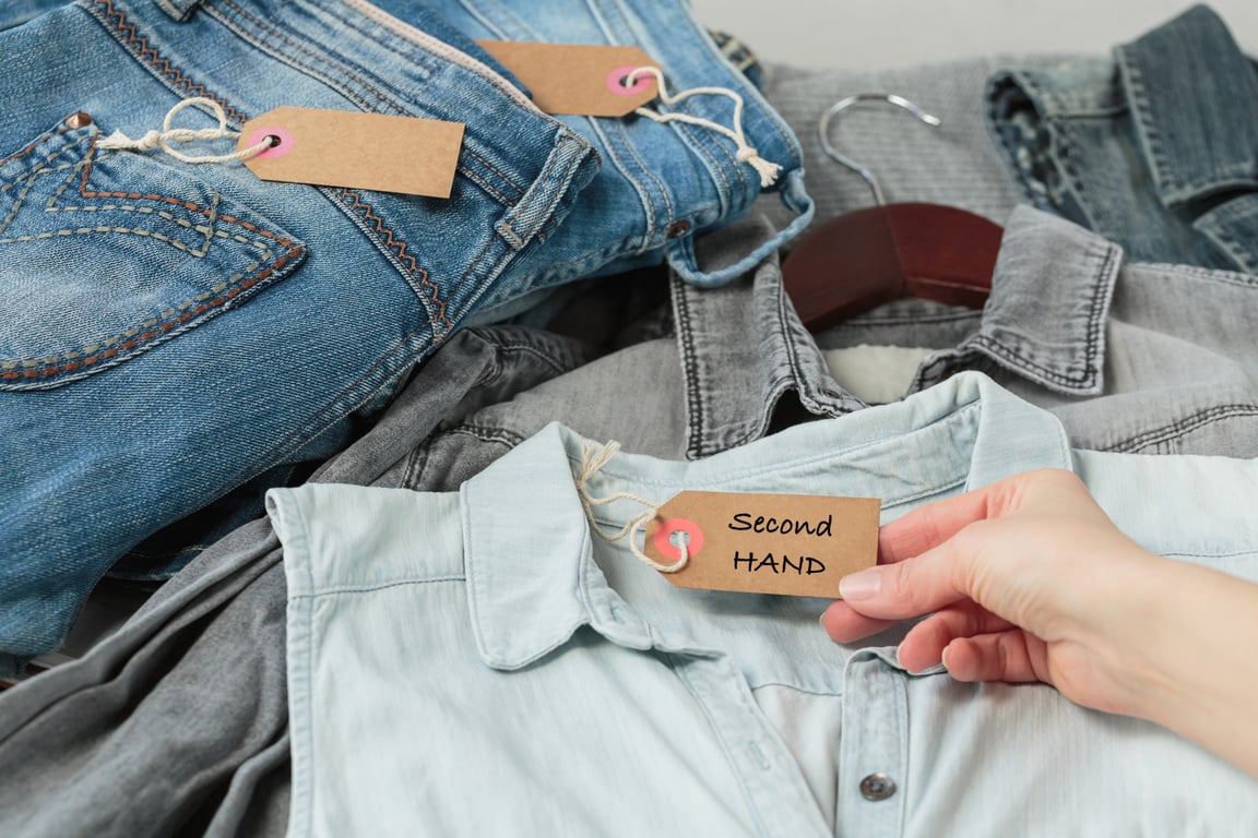 Womans hand holding tag with inscription second hand in store